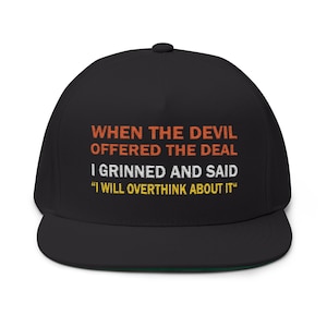 Puede incluir: Gorra de béisbol negra de ala plana con el texto "WHEN THE DEVIL OFFERED THE DEAL I GRINNED AND SAID 'I WILL OVERTHINK ABOUT IT'" en naranja y blanco. La gorra tiene la parte inferior verde.