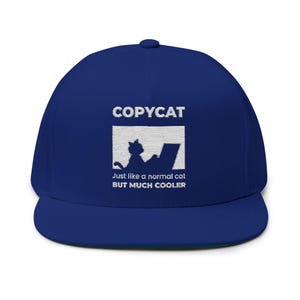 Może przedstawiać: Granatowa czapka z płaskim daszkiem. Z przodu biała grafika kota z laptopem, z tekstem "COPYCAT" i "Just like a normal cat BUT MUCH COOLER".