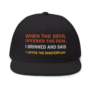 Puede incluir: Gorra de béisbol negra con visera plana y parte inferior verde. La gorra presenta el texto "WHEN THE DEVIL OFFERED THE DEAL I GRINNED AND SAID 'I OFFER THE MASTERPLAN'" en naranja y blanco. Un accesorio de moda.
