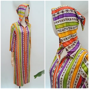 May include: A vintage, long-sleeved dress with a matching hood, displayed on a mannequin. The dress features vertical stripes in vibrant colors: orange, yellow, green, purple, and white. The hood and dress are adorned with a floral pattern.