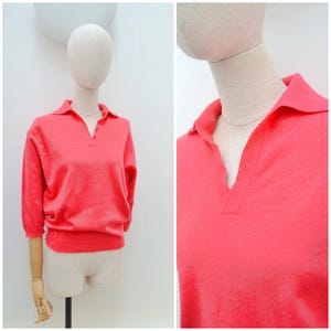 May include: A white ceramic mug with a black handle and the text "But First, Coffee" in a black, bold font. The mug is on a white surface. The mug is approximately 10 cm tall.