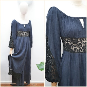 May include: A navy blue maxi dress with a square neckline and long sleeves. The dress features black lace detailing at the waist and sleeve cuffs. The dress is displayed on a mannequin.