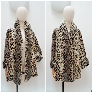 May include: A coat featuring a tan and black leopard print pattern. The garment has a wide collar, long sleeves with folded cuffs, and a straight hemline. The coat is displayed on a mannequin, showing both an open and a closed front view.