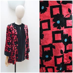 May include: A long-sleeved jacket featuring a vibrant red velvet base with a repeating pattern of black squares and black floral motifs. The center front panel and sleeve cuffs are solid black. Each black flower has a bright blue circular center.