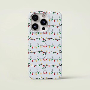 May include: A white phone case featuring a repeating pattern of colorful Christmas lights. The lights are red, green, and yellow, strung along black wires. The case has a glossy finish and a camera cutout.