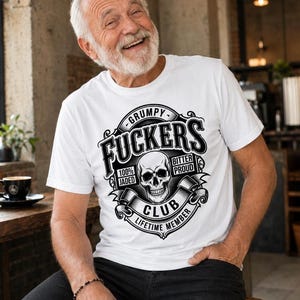 May include: White t-shirt with a black graphic that reads "Grumpy Fuckers Club Lifetime Member" with a skull in the center. The shirt is worn by a person.