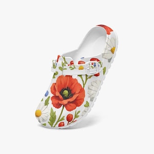 May include: A white slip-on clog featuring a vibrant floral pattern of large red poppies, white daisies, and small blue cornflowers. The shoe includes a functional white adjustable strap across the top with a matching buckle and a rounded toe design.