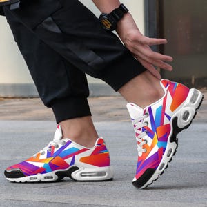 Puede incluir: Zapatillas deportivas vibrantes con un diseño geométrico colorido. Las zapatillas presentan una base blanca, una suela negra y un patrón multicolor de formas rojas, naranjas, azules y moradas. Los zapatos tienen cordones blancos y una suela acolchada.