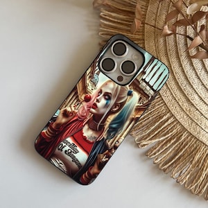 May include: Black phone case featuring a colorful illustration of a character with pink and blue pigtails, red lipstick, and a red jacket. The character is holding a lollipop. The case has a black border and a camera cutout.