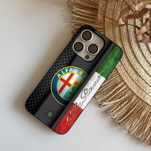 Puede incluir: Funda de teléfono negra con el logotipo de Alfa Romeo en un círculo azul con una cruz roja. La funda tiene una parte trasera texturizada y una franja vertical con la bandera italiana y la palabra "Alfa Romeo" en cursiva.