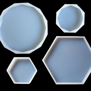 Könnte beinhalten: Vier Silikonformen zum Gießen von Harz. Die Formen haben verschiedene Formen, darunter eine runde, eine sechseckige und zwei kleinere sechseckige.