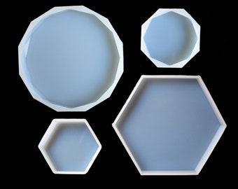 May include: Four silicone molds for resin casting. The molds are in different shapes, including a round, a hexagon, and two smaller hexagons.
