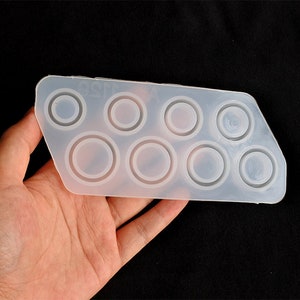 May include: A clear silicone mould with eight round cavities for making resin rings. The mould is flexible and has a smooth surface.