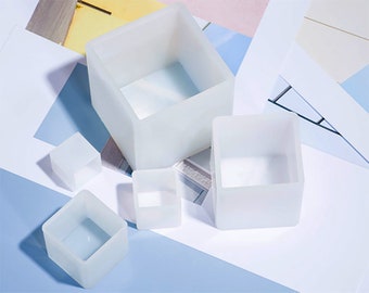 May include: Set of five white silicone square molds of varying sizes. The molds are made of flexible silicone and are perfect for making small crafts, such as soap, candles, or resin.