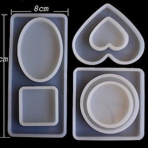 Op de afbeelding: Vier siliconen mallen voor het gieten van hars. De mallen zijn in de vorm van een hart, een vierkant, een rechthoek en een ovaal. De mallen zijn 8 cm breed en 18 cm hoog.