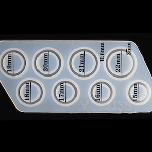 May include: Silicone mould with eight round cavities for making resin rings. The mould has measurements in millimetres for each cavity: 15mm, 16mm, 17mm, 18mm, 19mm, 20mm, 21mm, and 22mm.