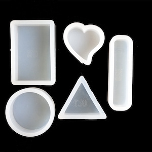 Puede incluir: Cinco moldes de silicona blancos para fundición de resina. Los moldes tienen forma de círculo, rectángulo, corazón, triángulo y rectángulo largo.
