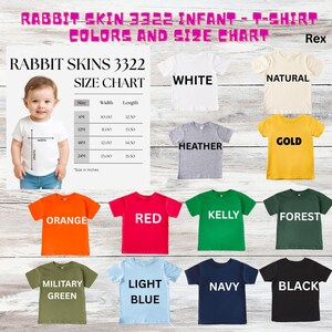 May include: A color chart for Rabbit Skins 3322 infant t-shirts. The chart displays various colors, including white, natural, heather, gold, orange, red, kelly green, forest green, military green, light blue, navy, and black. A size chart is also included.