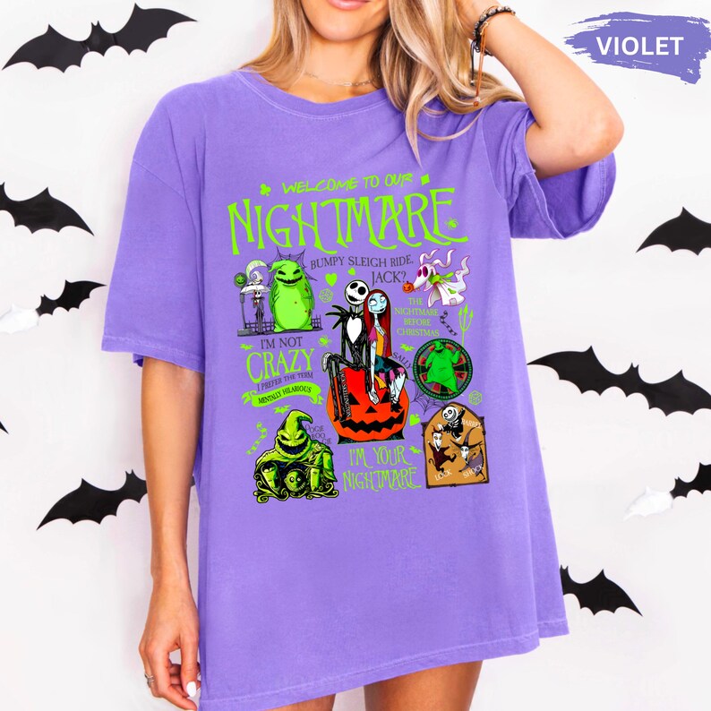 Puede incluir: Una camiseta de color violeta con un dise&ntilde;o gr&aacute;fico de "Pesadilla antes de Navidad". El dise&ntilde;o incluye personajes y frases como "Welcome to our Nightmare", "I'm not crazy" y "I'm your nightmare".