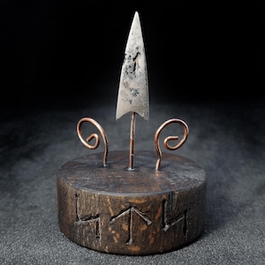 Punta de flecha de combate escita de bronce: artefacto antiguo de 2500 años de antigüedad sobre un soporte de madera con runas celtas.