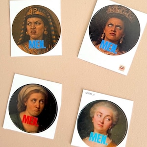 Op de afbeelding: Vier ronde stickers met vintage portretten van vrouwen, elk met het woord "MEN" in vette letters. De portretten tonen verschillende uitdrukkingen. De tekst is in blauw en rood.