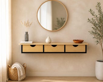 May include: A wall-mounted floating console table featuring three light wood drawers with black frames and circular cut-out handles. Above the console hangs a large round mirror with a thin light wood frame, reflecting the interior space.