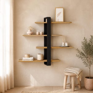 Può includere: Una scaffalatura a parete caratterizzata da una struttura verticale in metallo nero con quattro ripiani orizzontali in legno chiaro che si estendono lateralmente. I ripiani ospitano vari oggetti decorativi, tra cui una stampa incorniciata, candele e libri.