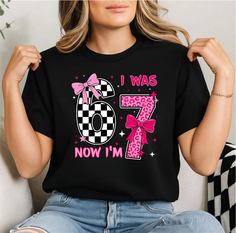 Peut inclure: T-shirt noir avec le texte "I WAS 67 NOW I'M" en rose. Le chiffre 67 est d&eacute;cor&eacute; d'un motif &agrave; carreaux et d'un imprim&eacute; l&eacute;opard, agr&eacute;ment&eacute; de n&oelig;uds et d'&eacute;toiles roses. Un t-shirt d'anniversaire amusant.
