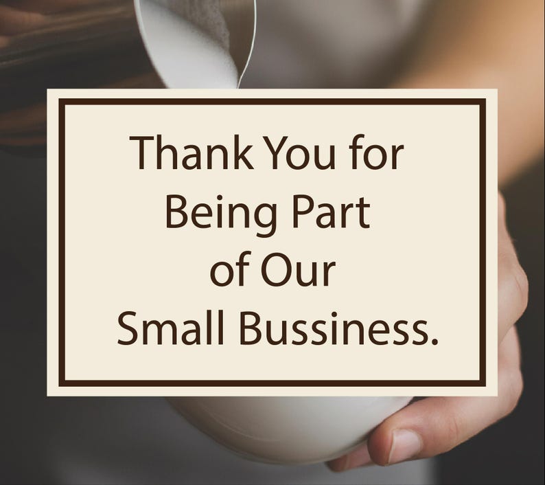 May include: A cream-coloured card with a dark brown border displays the text "Thank You for Being Part of Our Small Business." The card is held in a person's hand, with a white cup in the foreground.