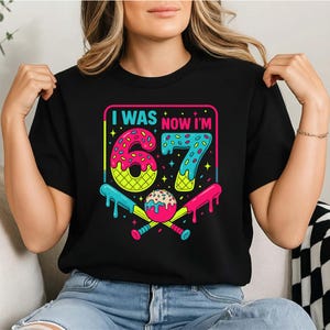 Peut inclure: T-shirt noir avec un motif color&eacute; indiquant "I WAS NOW I'M 67". Le chiffre 67 est con&ccedil;u sur le th&egrave;me des beignets et des cornets de glace, avec des battes de baseball et une balle. Un cadeau d'anniversaire amusant.