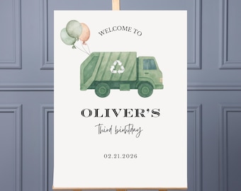 May include: A welcome sign for Oliver's third birthday, featuring a green garbage truck illustration with balloons. The sign includes the text "WELCOME TO" above the truck, and "OLIVER'S Third birthday" below, with the date 02.21.2026.