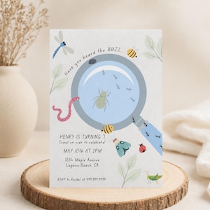 May include: A rectangular invitation card featuring a magnifying glass graphic surrounded by illustrations of a dragonfly, worm, bees, ladybug, and grasshopper. The text reads: Have you heard the BUZZ... HENRY IS TURNING 7 Crawl on over to celebrate! MAY 10th AT 2PM 1234 Maple Avenue Laguna Beach, CA RSVP to Rachel at 999.999.9999.