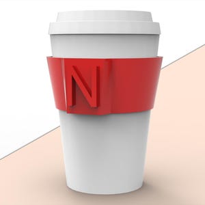 Può includere: Una tazza da caffè bianca con una fascia rossa con la lettera "N". La tazza ha un coperchio bianco ed è posta su uno sfondo bianco e pesca. Le parole "elegant and natural" sono nell'angolo in basso a destra.