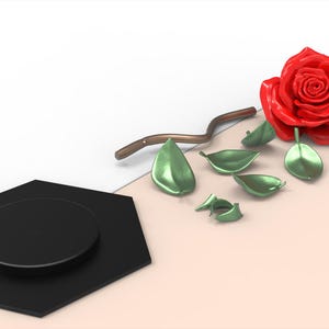 May include: A glossy red rose head, a curved brown stem, and several detached metallic green leaves arranged near a black hexagonal base. The image includes a small logo in the bottom right corner with the text elegant and natural.