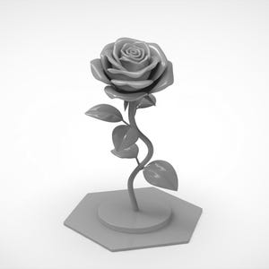 May include: A monochromatic gray sculpture of a single rose with a detailed bloom, a curved stem, and several leaves. The rose is attached to a circular base, which is mounted on a flat, hexagonal platform, creating a unified, solid gray object.