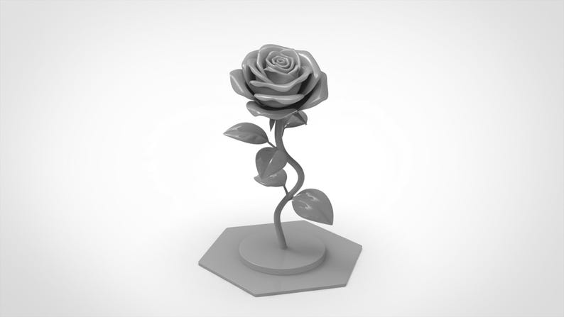 May include: A monochromatic gray sculpture of a single rose with a detailed bloom, a curved stem, and several leaves. The rose is attached to a circular base, which is mounted on a flat, hexagonal platform, creating a unified, solid gray object.