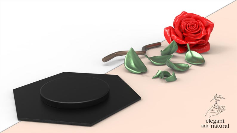 May include: A black hexagonal display stand with a circular top platform, accompanied by a red rose flower, a brown stem, and several detached green leaves. The image includes a small logo with a hand illustration and the text elegant and natural.