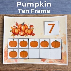 Peut inclure: Une fiche pédagogique Pumpkin Ten Frame avec un fond beige et des feuilles d'automne orange. La feuille affiche un grand chiffre 7 dans un carré et sept illustrations individuelles de citrouilles orange placées dans une grille de dix.
