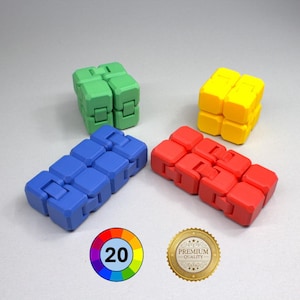 May include: Four colourful fidget cubes in green, yellow, blue, and red. Each cube is made of interlocking blocks that can be manipulated. A colour wheel with the number 20 and a gold "Premium Quality" seal are also in the image.