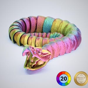 May include: A multi-coloured articulated snake toy in shades of pink, green, and gold. The snake's head is open, revealing a detailed design. The toy is made of multiple segments, allowing for flexible movement. The image also includes a colour wheel with the number 20 and a gold seal.