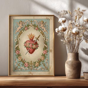 Può includere: Stampa incorniciata in stile vintage con un cuore rosso trafitto da una spada, circondato da rose e una ghirlanda floreale. Due cherubini e croci adornano la parte superiore e inferiore. La stampa è in una cornice dorata, su sfondo azzurro.