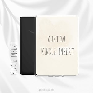 Könnte beinhalten: Ein schwarzes Kindle-Gerät mit einer transparenten Schutzhülle. Die Hülle trägt den Text "CUSTOM KINDLE INSERT" in einer handschriftlichen Schriftart auf beigem Hintergrund. Die Worte "KINDLE INSERT" sind vertikal auf der linken Seite aufgedruckt.