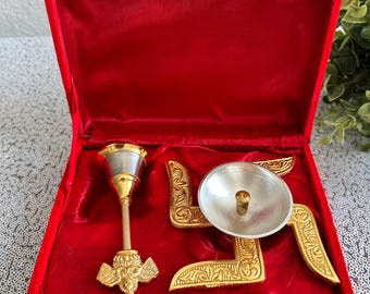 May include: A red velvet box with a gold clasp, containing a gold and silver religious item. The item includes a gold-colored stand with a silver bowl and a gold-colored item with a detailed design.