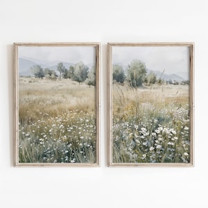 May include: Two framed wall art prints featuring a landscape painting of a field filled with white daisy flowers, tall grasses, and green trees under a soft, hazy sky. The artwork displays muted earth tones, including beige, green, and white.