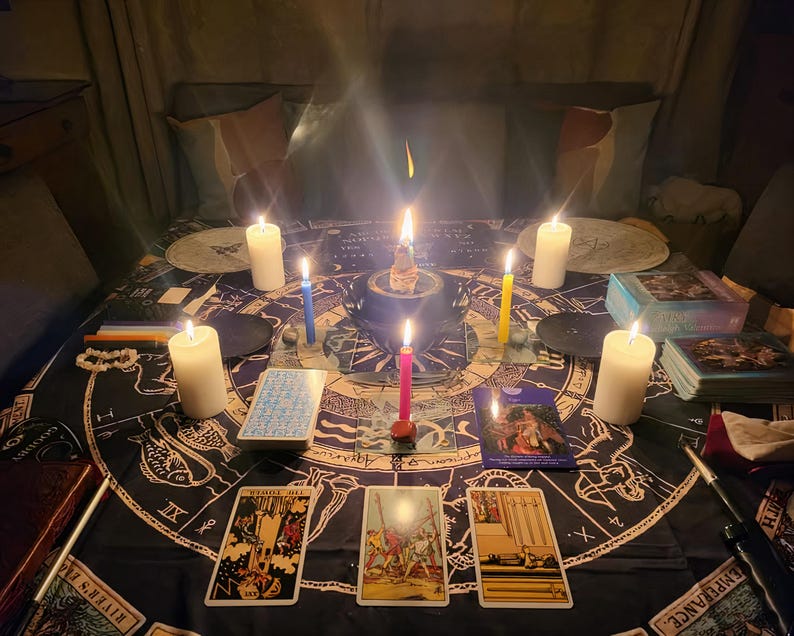 Puede incluir: Una escena m&iacute;stica con velas encendidas, cartas del tarot y un altar central. La disposici&oacute;n incluye velas de varios colores, barajas de tarot y un mantel oscuro con s&iacute;mbolos celestiales. El ambiente es tenue, creando una atm&oacute;sfera espiritual.