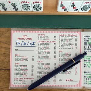 K&ouml;nnte beinhalten: Eine To-Do-Liste f&uuml;r das Spiel Mahjong, mit einem blauen Stift auf rosa und wei&szlig;em Papier. Die Liste enth&auml;lt Abschnitte f&uuml;r Quinten, Consecutive Run und Any Like Numbers.