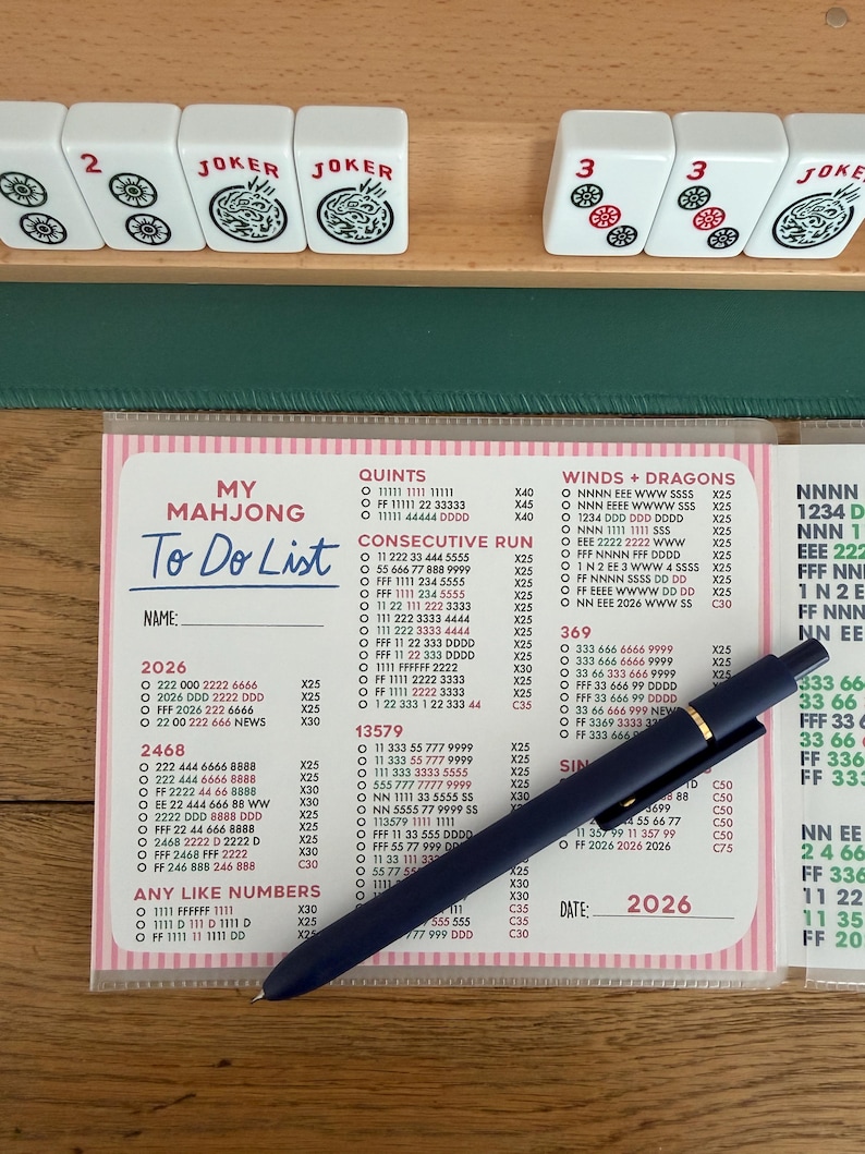 K&ouml;nnte beinhalten: Eine To-Do-Liste f&uuml;r das Spiel Mahjong, mit einem blauen Stift auf rosa und wei&szlig;em Papier. Die Liste enth&auml;lt Abschnitte f&uuml;r Quinten, Consecutive Run und Any Like Numbers.