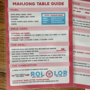 May include: A pink and white Mahjong Table Guide card with detailed instructions. The guide lists tiles, suits, and card information. The card also includes instructions for The Deal and The Charleston.