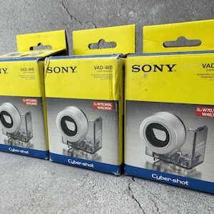 May include: Three yellow and black Sony Cyber-shot lens adapter boxes. Each box features a silver lens adapter and the text "VAD-WB Lens Adaptor". The boxes are labeled for W70, W50, W40, and W30 models.