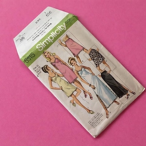 May include: Vintage Simplicity sewing pattern envelope featuring illustrations of women's dresses. The envelope is white with green text and the number 3515. The background is a solid pink color.